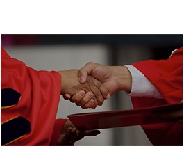 Graduate shaking hands and receiving their diploma during Commencement.