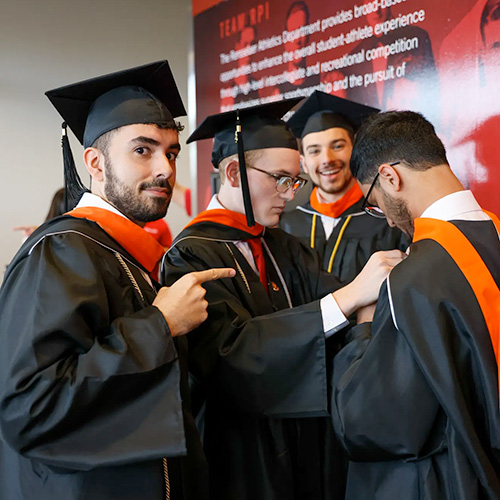 Students in their cap and gowns help each other fix their robes